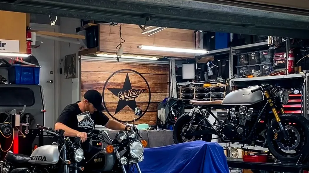 Cafe Racer Garage workshop with cafe racer motorcycles parked and a rider working on one of the bikes