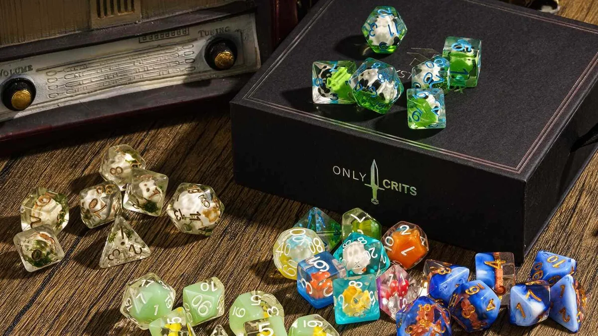 Only Crits mystery box dice collection laid out on a table beside the black gift box